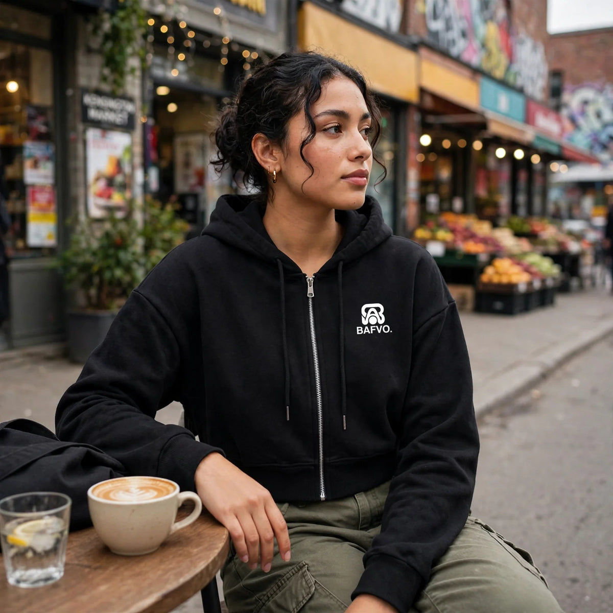 Woman wearing a black BAFVO cropped zip-up hoodie at a Kensington Market cafe in Toronto
