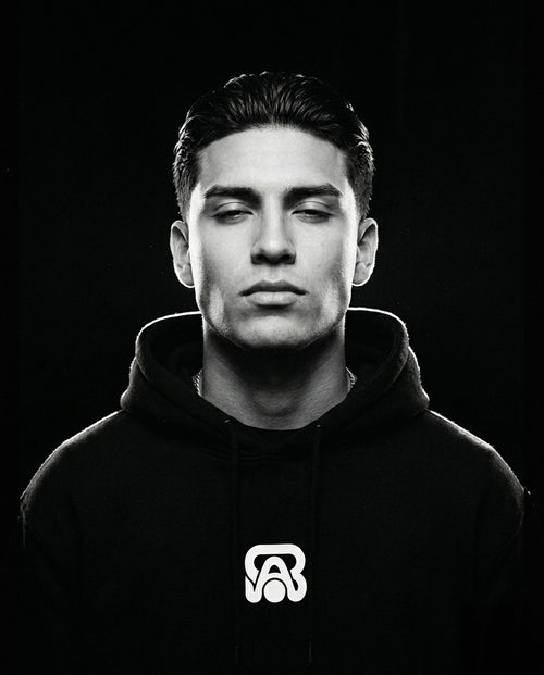 Portrait studio en noir et blanc d'un homme portant un sweat à capuche BAFVO noir avec un logo blanc