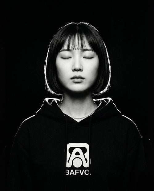 Portrait de studio en noir et blanc d'une femme au carré portant un sweat à capuche noir BAFVO